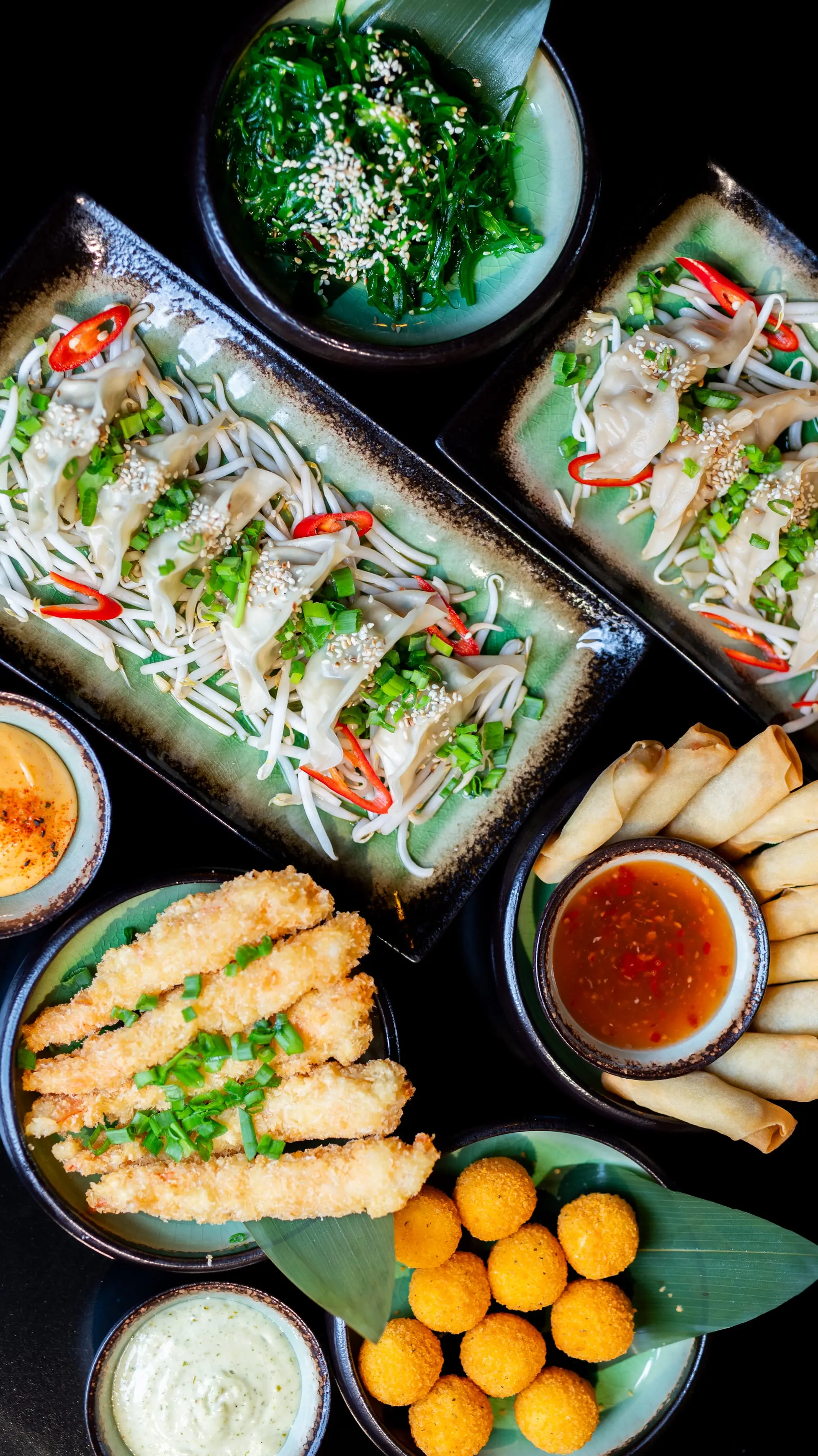 Zestaw przystawek azjatyckich — tempura, sajgonki, wakame i sosy w Sushi Okami 2.0 Oleśnica